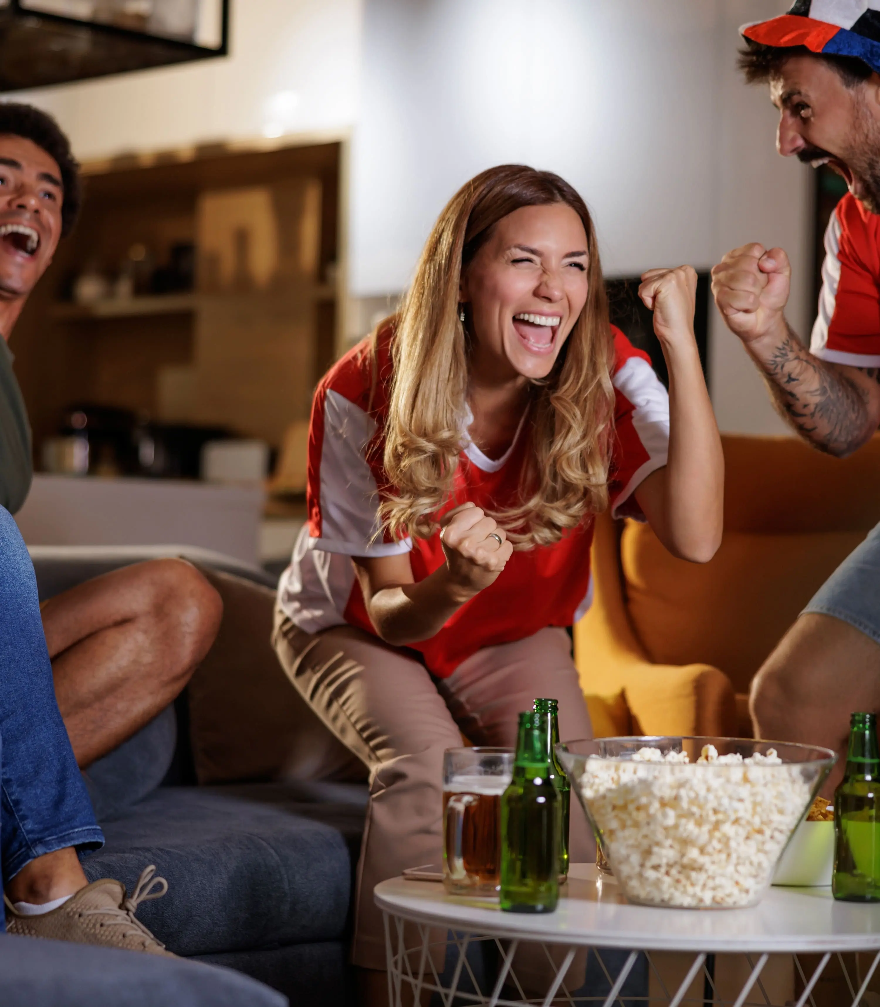 Group of young people watching and celebrating football match on television.