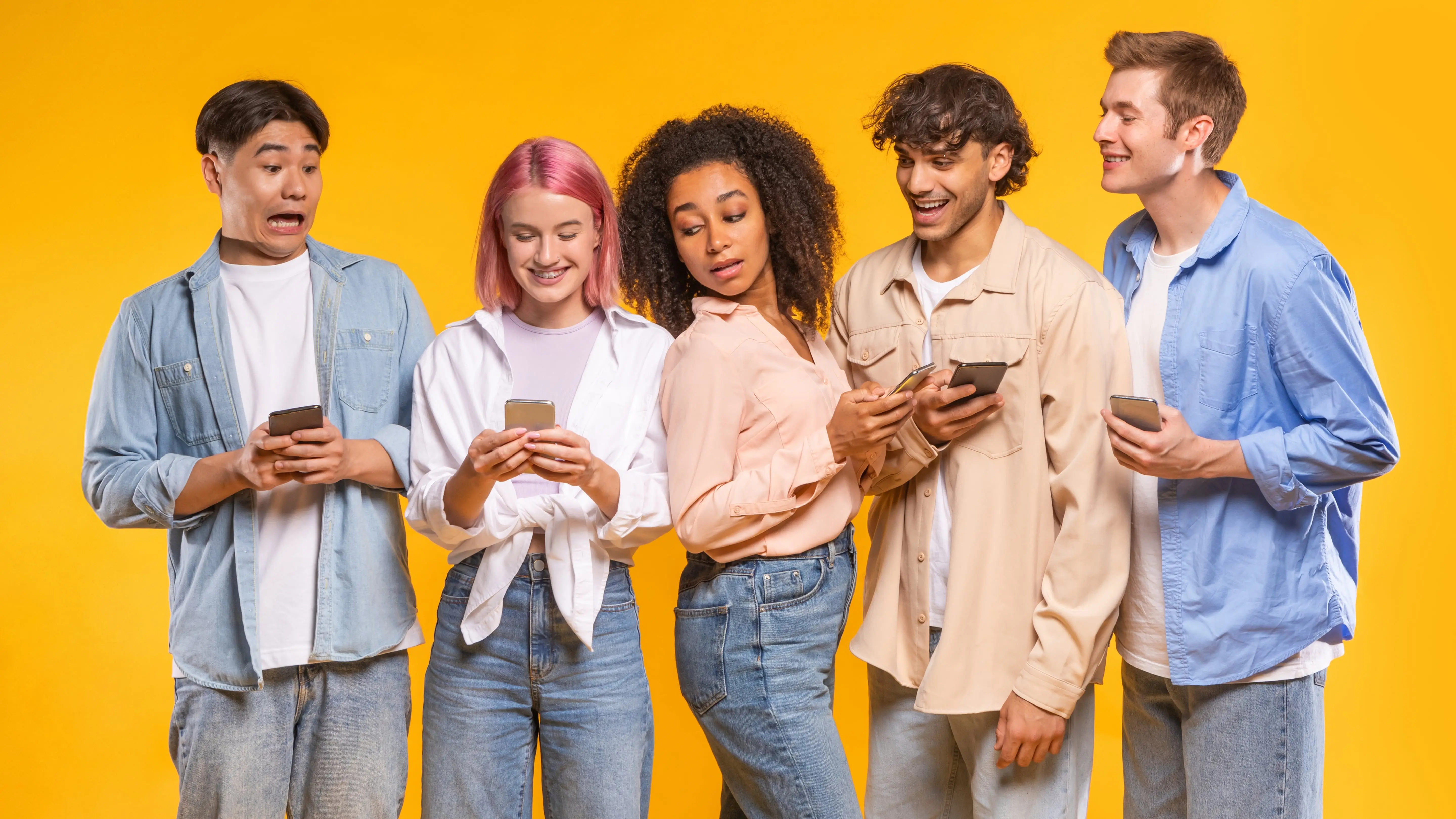 A group of five gen z interacting with each other while looking at their phone.